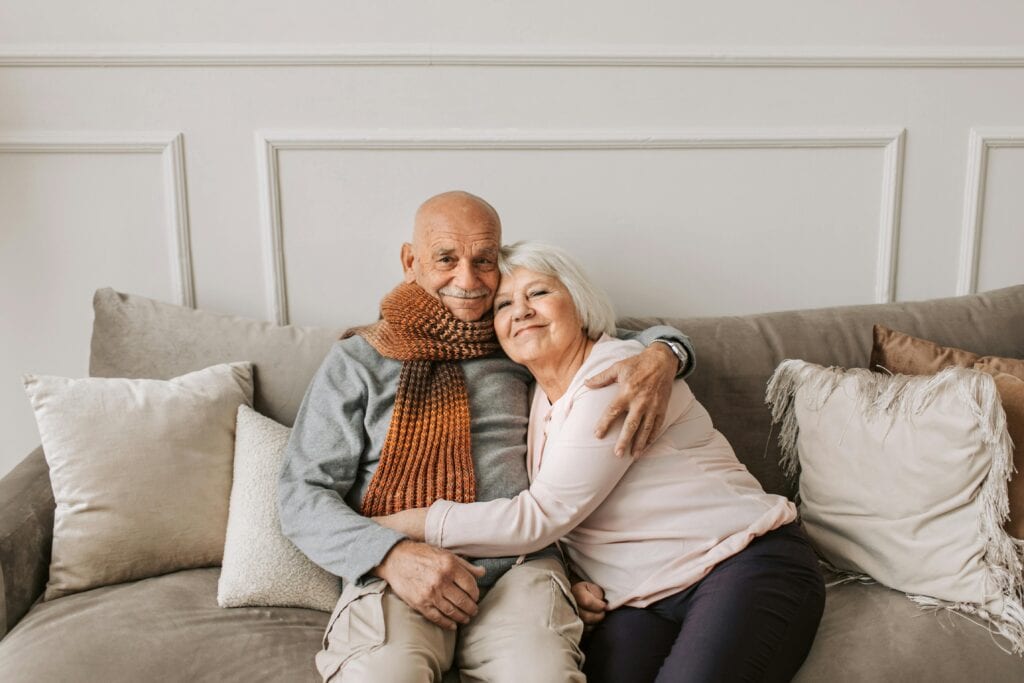 Happy elderly couple hugging each other on a comfortable sofa